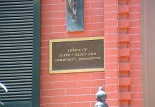 Closeup of plaque on exterior red-brick wall, which reads Office of Faith-Based and Community Initiatives