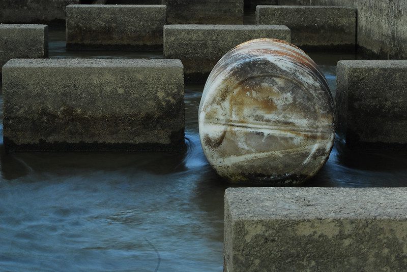 Among a group of large rectangular concrete blocks is a concrete cylinder, echoing the idea of round and square pegs