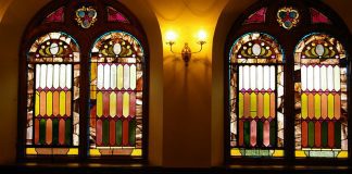 Four stained-glass windows, seen from inside the church.