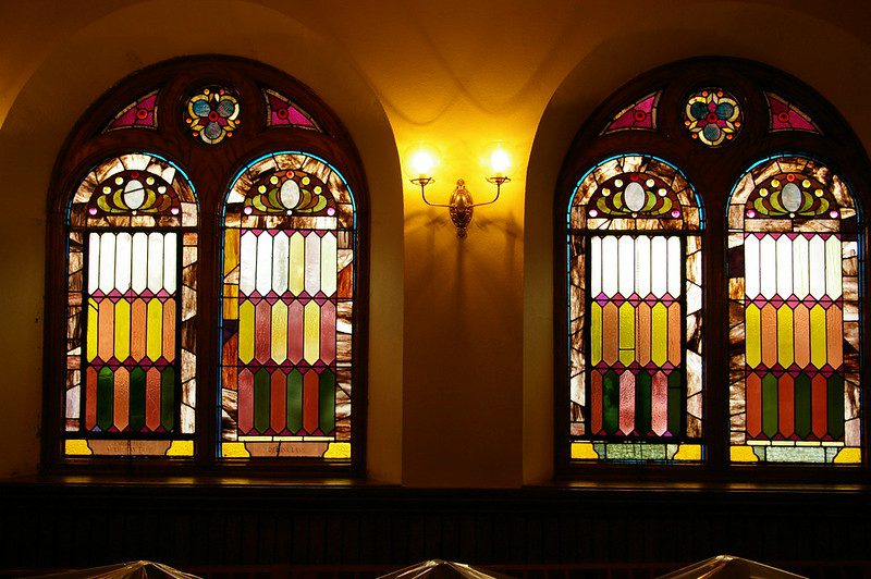 Four stained-glass windows, seen from inside the church.