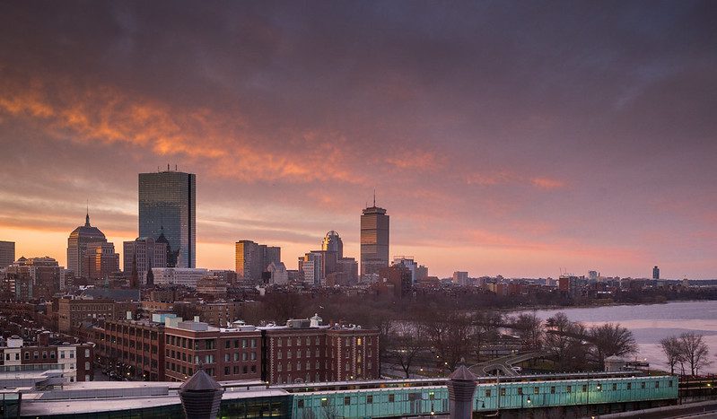 A winter afternoon view of Boston, seen from the south, with an orangey sky behind the city skyline.