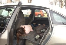 Through an open car door, two sleeping children are visible