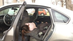 Through an open car door, two children are lying on an air mattress.