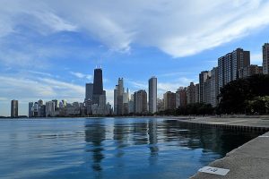 A view of the Chicago skyline on a sunny day with some clouds in the sky.