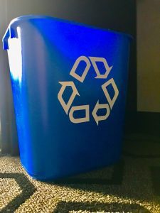 close up photo of blue recycling bin on brown carpet