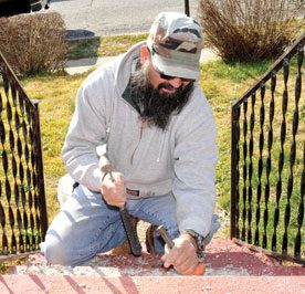 NSP: illustration photo is of man with hammer and chisel working on front steps of a house