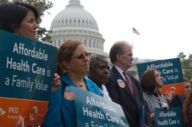 With the Capitol in the distance, the photo shows a row of people holding signs reading "Affordable Health Care is a Family Value." The people, representing faith-based organizing, are two white women, an older black woman, a white man, and another white woman.