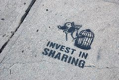 sidewalk stencil that reads, "Invest in Sharing"