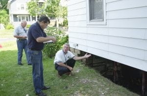 FEMA inspector and city inspectors examine the foundation of a house.