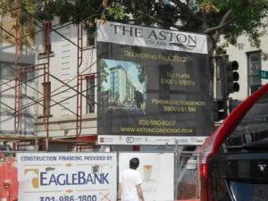 Photo of urban street shows a large billboard for a new development to be built, representing neighborhood change