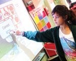 A girl with a pony tail points at a dialogue box on a large screen in a classroom, at Monarch, a school funded by an impact investment from Clearinghouse CDFI that provides quality education, safe environment, and support services to homeless youth.