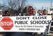 Ralliers gather in Washington, D.C., with a sign that reads "Stop, Don't close public schools."