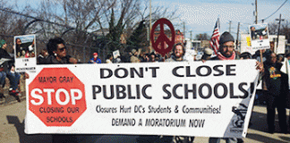 Ralliers gather in Washington, D.C., with a sign that reads "Stop, Don't close public schools."