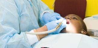 A female dentist cleans a young boy's teeth.