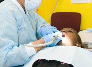 A female dentist cleans a young boy's teeth.