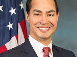 HUD Secretary Julian Castro poses in a formal headshot in front of an American flag.