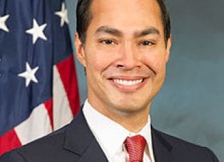 HUD Secretary Julian Castro poses in a formal headshot in front of an American flag.