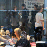 View of people on a sidewalk from inside a restaurant.