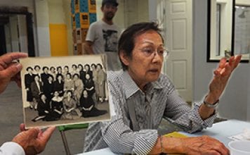 A woman tells her story about life in Little Tokyo while someone holds an old photo of her and her coworkers.