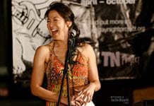 Poet traci kato-kiriyama laughs at the microphone.