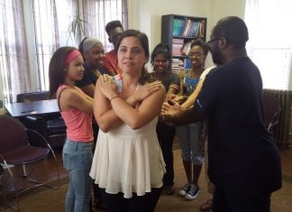 A member of a New Jersey based advocacy group crosses her hands over her chest and her fellow group members line up behind her with their arms extended. This is a trust fall.