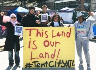 Residents of four historically African-American neighborhoods hold up a sign that reads "This Land is Our Land! #TentCityATL"