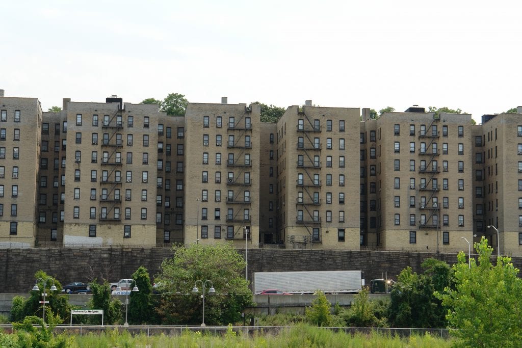 A row of tall apartment buildings, the University Heights residential complex in the Bronx, New York, illustrating article about AMI