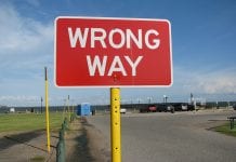 Red road sign that says "Wrong Way"