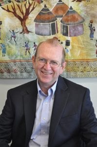 The Rev. John Edgar sits in front of a tapestry.