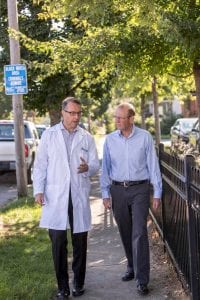 Dr. Kelly Kelleher and the Rev. John Edgar walk down a street in Columbus, Ohio.