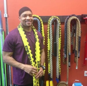 An African-American man smiles in his gym, which he opened thanks to a loan he received due to his character, not his credit score. Character lending is gaining steam again.