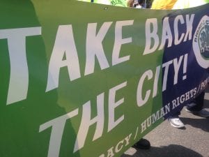 A green and blue banner with the words "Take back the city" and part of a logo visible on the right side.