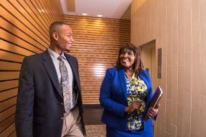 Two employees of Grace Federal Solutions in North Carolina, an African-American man and woman, chat in the hallway of their offices. The company secured a loan from a CDFI.