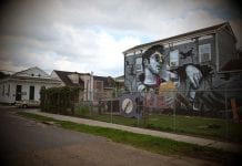 A sprawling white “hipster” is memorialized against a backdrop of romanticized visions of blight in a mural that dominates an intersection in the historically Black 7th Ward in New Orleans.