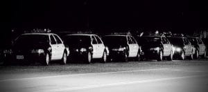 Black and white photo of a row of police cars.