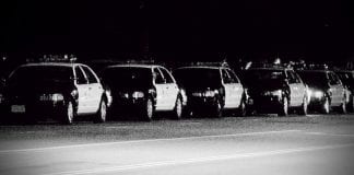 Black and white photo of a row of police cars.
