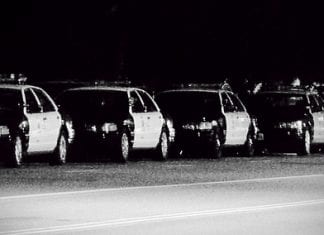Black and white photo of a row of police cars.