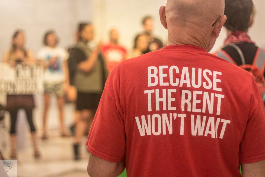 Close-up of the back of a t-shirt that says "Because the rent won't wait." Serial eviction filings are up in Atlanta.