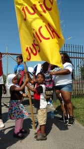 Two small children holding up a flag that says 'Justicia.'