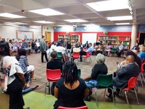 People seated in circle within a larger circle in a library-type room.