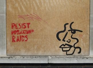 Boarded window with "Resist Immigration Raids" sprayed.