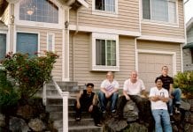A group of people stand outside a home used for transitional housing after it lost funds due to the City of Seattle diverting resources to rapid re-housing.