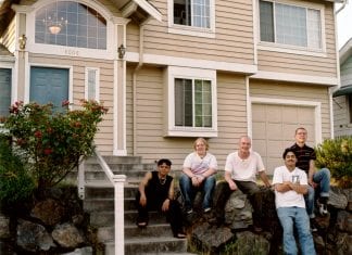 A group of people stand outside a home used for transitional housing after it lost funds due to the City of Seattle diverting resources to rapid re-housing.