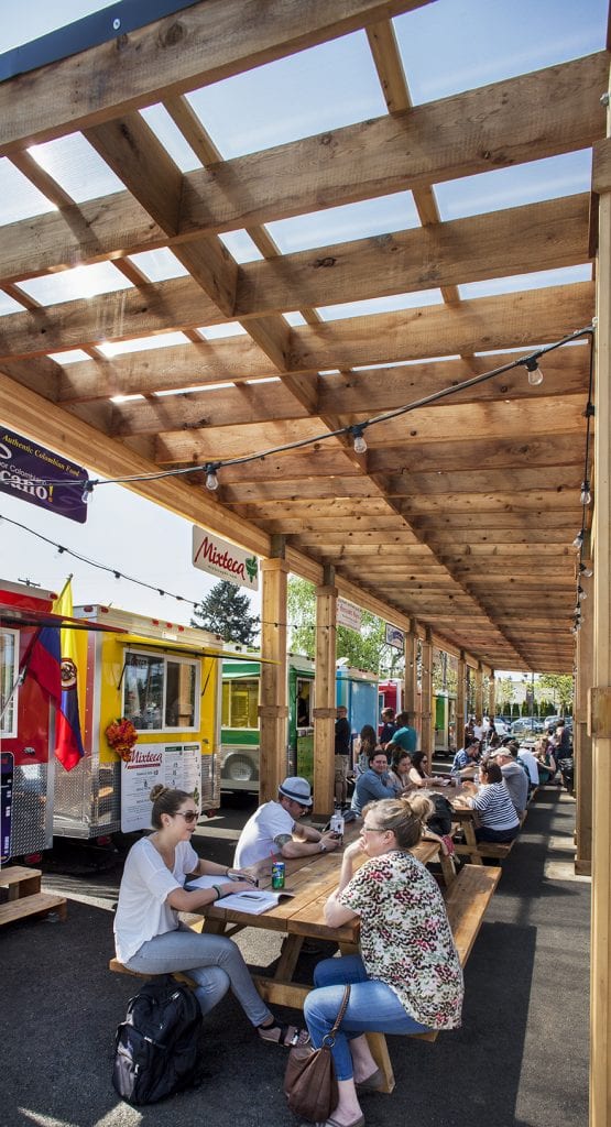 People sit at picnic tables at the Portland Mercado. This is an example of food-oriented development.