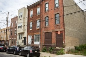 A solid-looking rowhouse in Philadephia that is surrounded by homes that are in need of repairs.