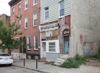 An exterior view of a rowhouse in Philadelphia, Pennslyvania that appears to have some water damage.