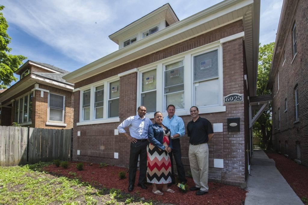 A group of people stand in front rental housing in Chicago that was rehabbed.