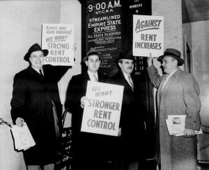 Men in topcoats and hats with rent increase protest signs.