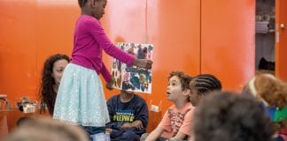 Child showing a story book to another child.