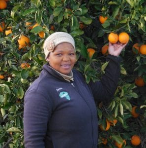 Woman posed in front of an orange tree.